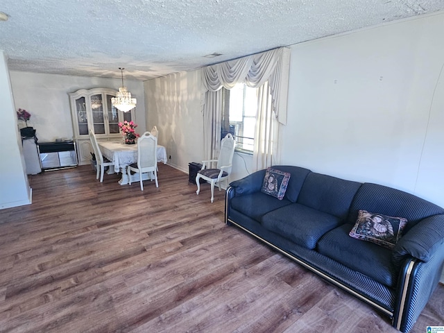 living room featuring a notable chandelier, dark wood-type flooring, and a textured ceiling