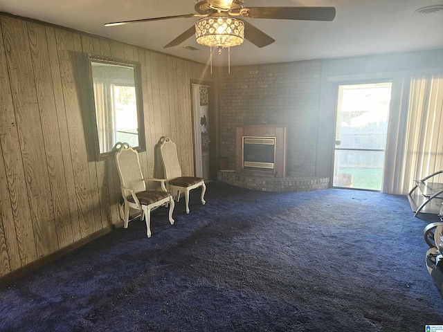 sitting room with brick wall, wood walls, a fireplace, and carpet floors