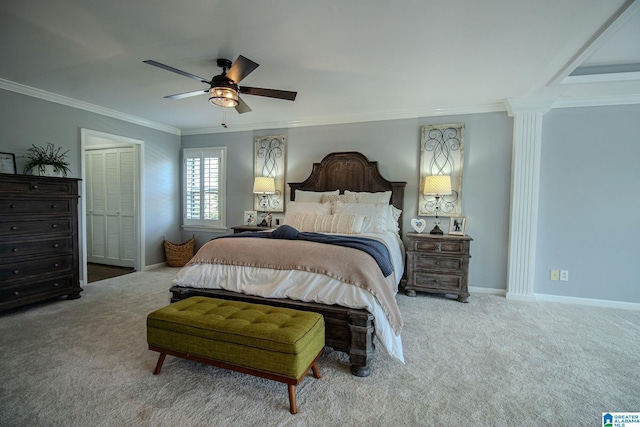 carpeted bedroom featuring a closet, ceiling fan, crown molding, and decorative columns