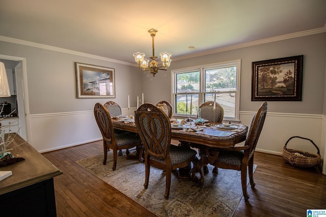 dining area with dark wood-type flooring, ornamental molding, and an inviting chandelier