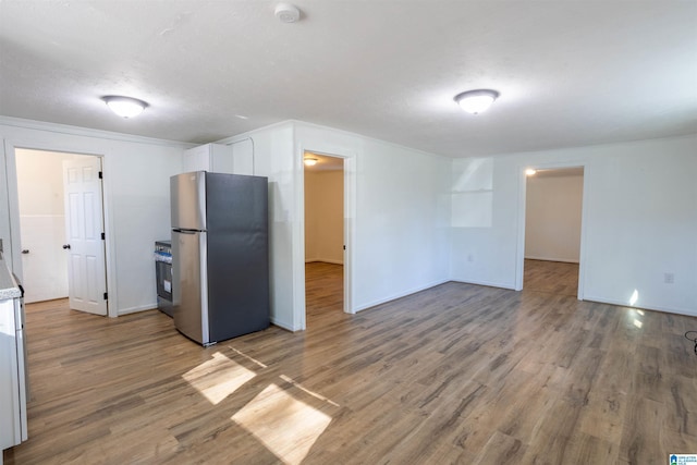 kitchen with white cabinets, stainless steel refrigerator, hardwood / wood-style floors, and stove