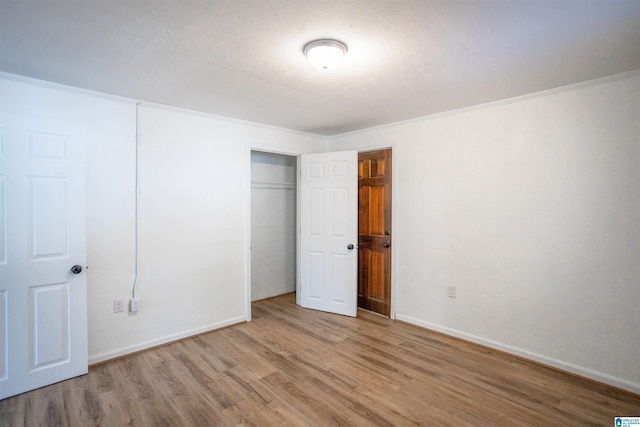 unfurnished bedroom with wood-type flooring, a closet, crown molding, and a textured ceiling