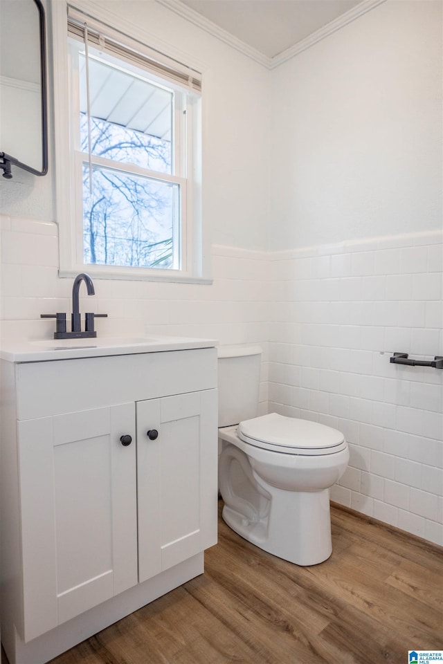 bathroom featuring vanity, tile walls, toilet, hardwood / wood-style flooring, and crown molding