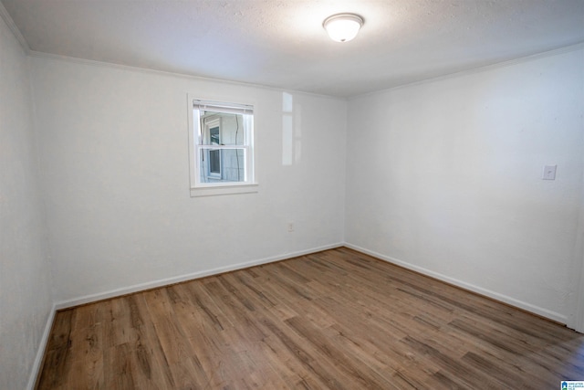 empty room with hardwood / wood-style floors, a textured ceiling, and crown molding