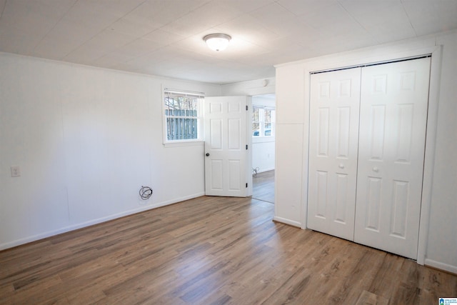 unfurnished bedroom featuring hardwood / wood-style flooring, a closet, and crown molding