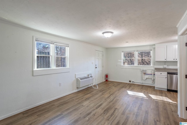 spare room featuring crown molding, light hardwood / wood-style floors, a textured ceiling, and a wall unit AC