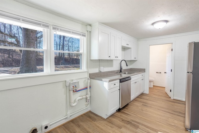 kitchen with sink, light wood-type flooring, white cabinetry, and appliances with stainless steel finishes