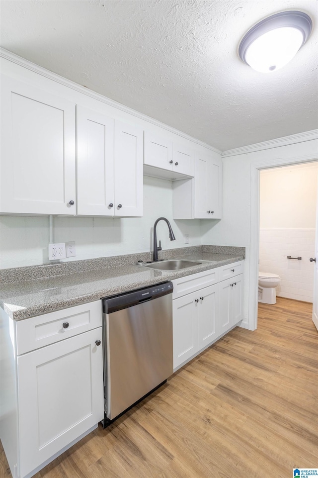 kitchen with a textured ceiling, white cabinets, sink, light wood-type flooring, and stainless steel dishwasher