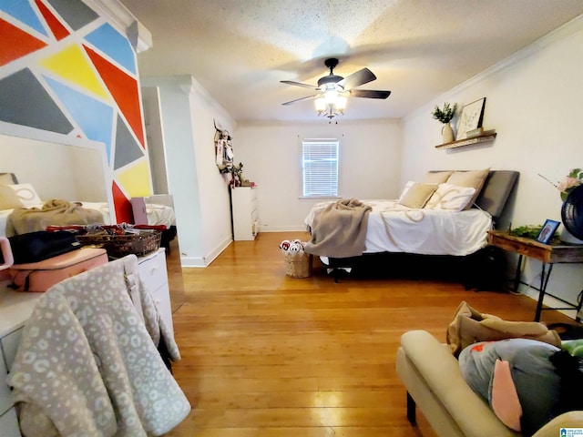 bedroom with ceiling fan, ornamental molding, wood-type flooring, and a textured ceiling