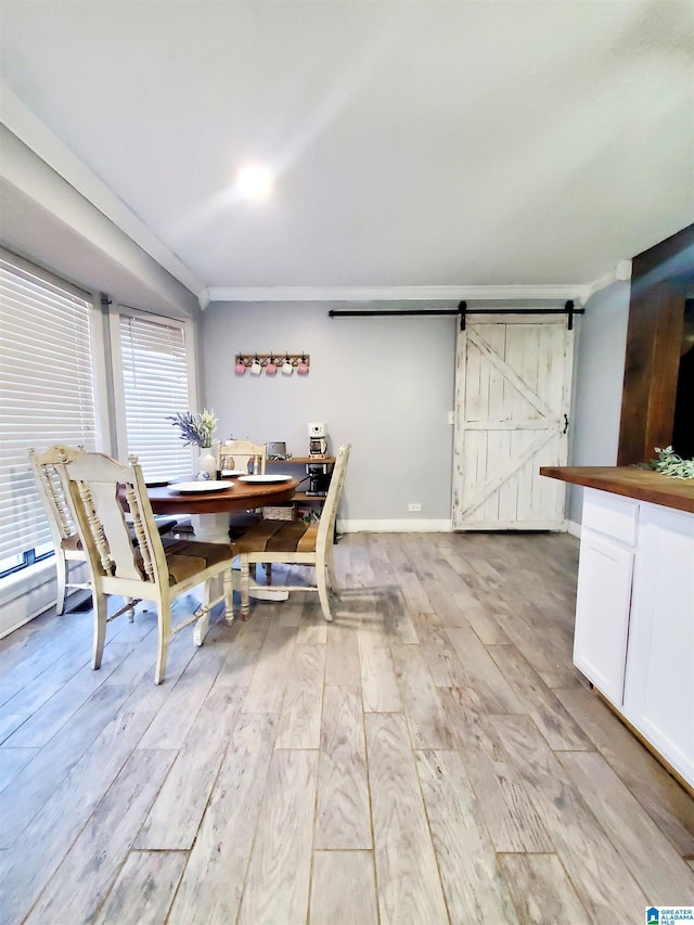 dining area featuring ornamental molding, a barn door, and light wood-type flooring