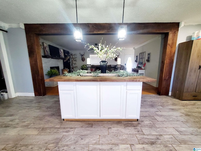 kitchen with decorative light fixtures, wooden counters, white cabinets, and a center island