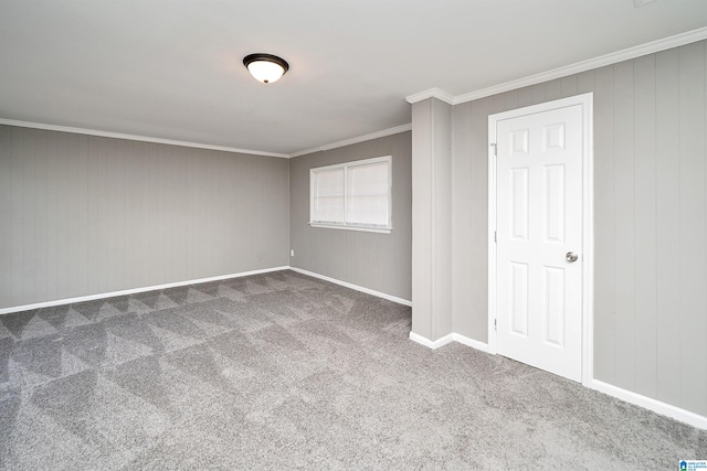 carpeted empty room featuring wood walls and crown molding