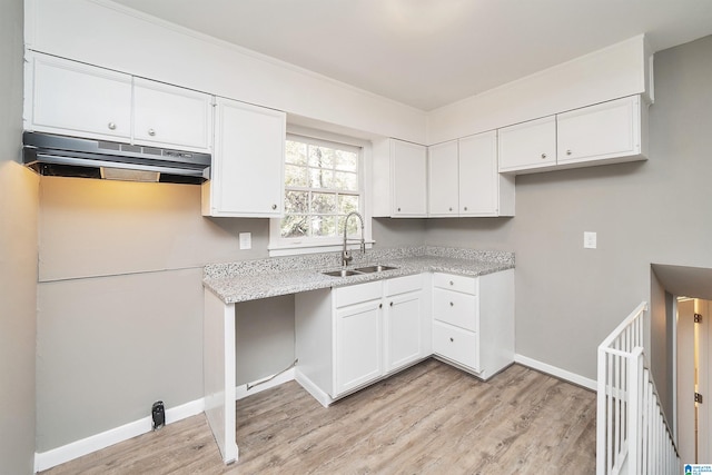 kitchen with light stone counters, sink, white cabinetry, and light hardwood / wood-style flooring