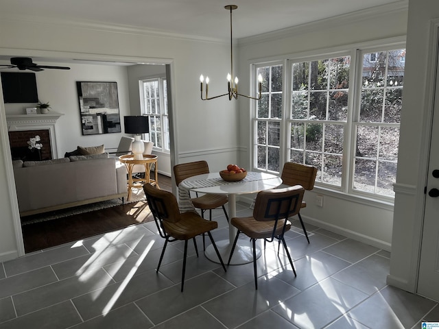 tiled dining space featuring ornamental molding, ceiling fan with notable chandelier, and a wealth of natural light