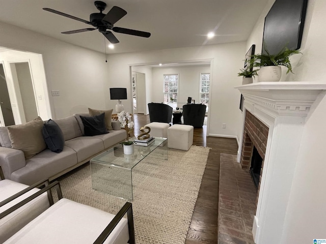 living room with a fireplace, dark hardwood / wood-style floors, and ceiling fan