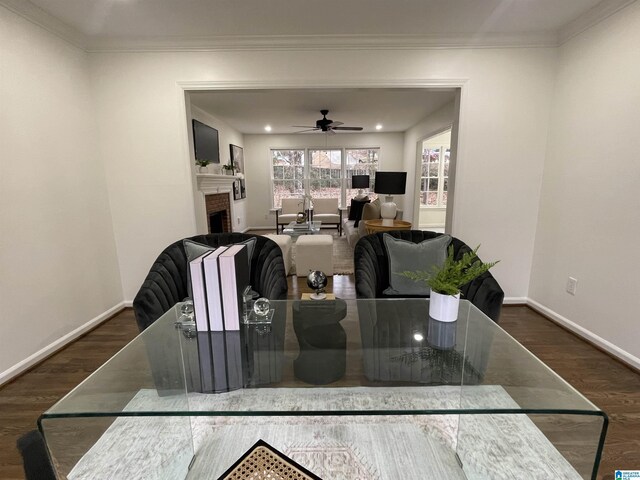 dining space featuring dark hardwood / wood-style flooring, a fireplace, ornamental molding, and ceiling fan