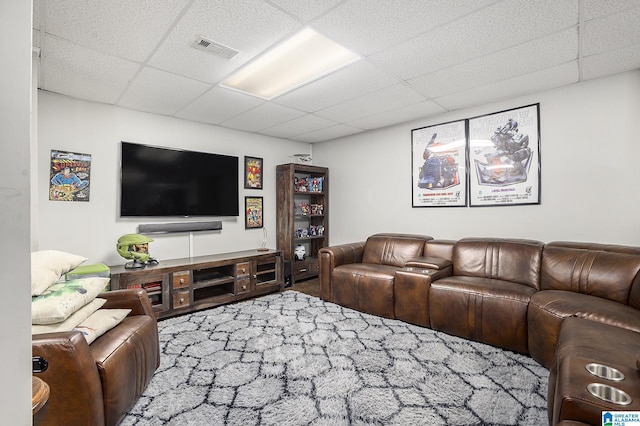 living room featuring a drop ceiling and carpet