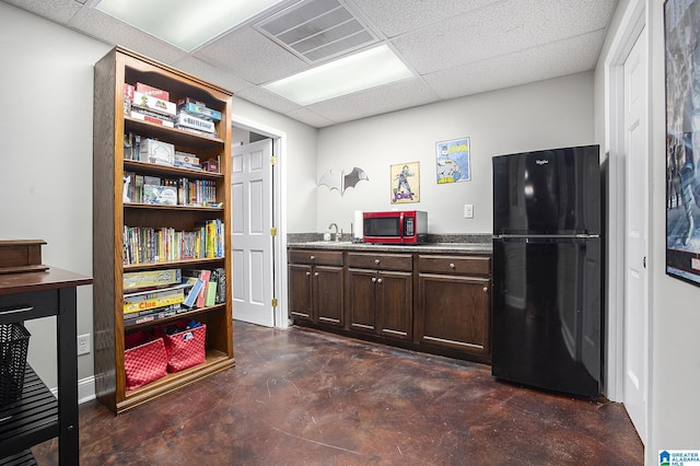 kitchen featuring black refrigerator, a paneled ceiling, and dark brown cabinets