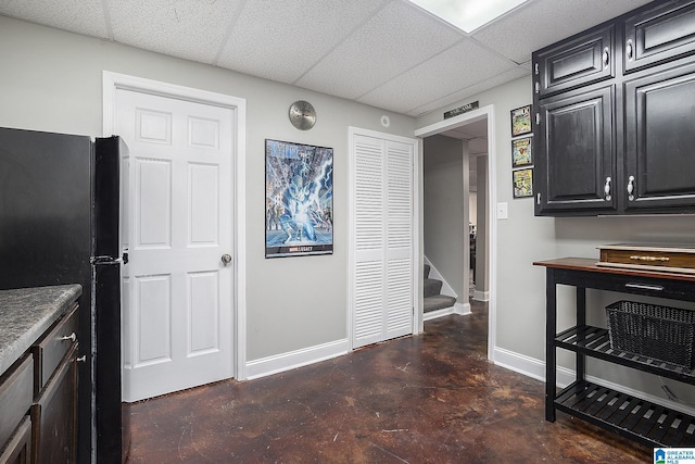 kitchen featuring a paneled ceiling and black fridge