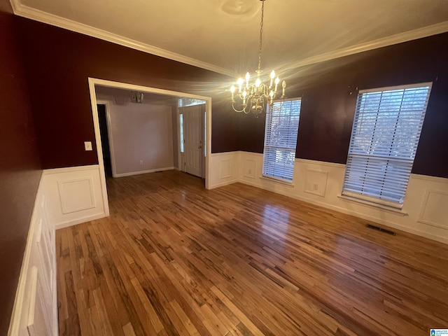 unfurnished dining area featuring hardwood / wood-style flooring, a chandelier, and ornamental molding