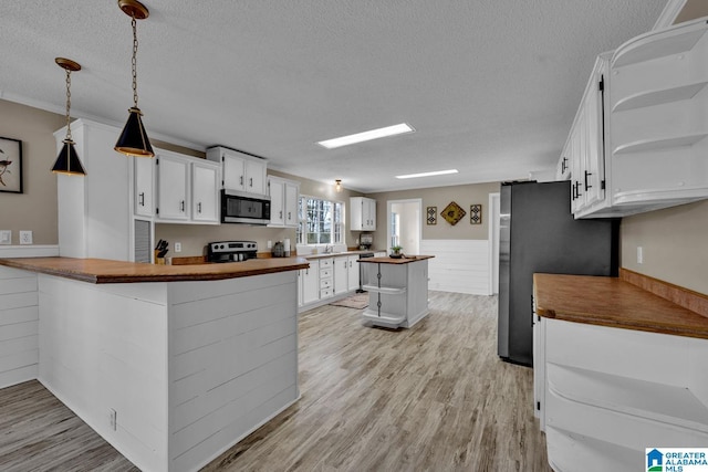 kitchen with a textured ceiling, white cabinets, wooden counters, stainless steel appliances, and kitchen peninsula