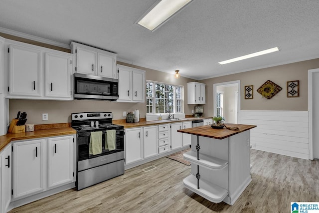 kitchen with white cabinetry, butcher block counters, and appliances with stainless steel finishes