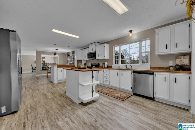 kitchen featuring decorative light fixtures, white cabinetry, butcher block counters, and appliances with stainless steel finishes