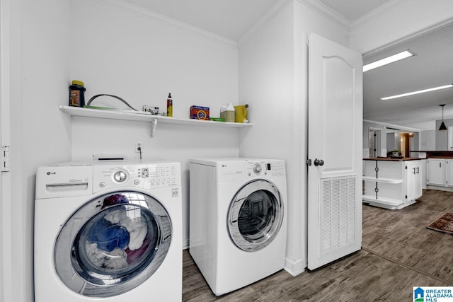 washroom featuring dark wood-type flooring, separate washer and dryer, and ornamental molding