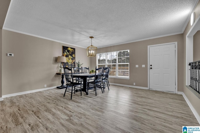 dining area with a textured ceiling, ornamental molding, a notable chandelier, and light wood-type flooring