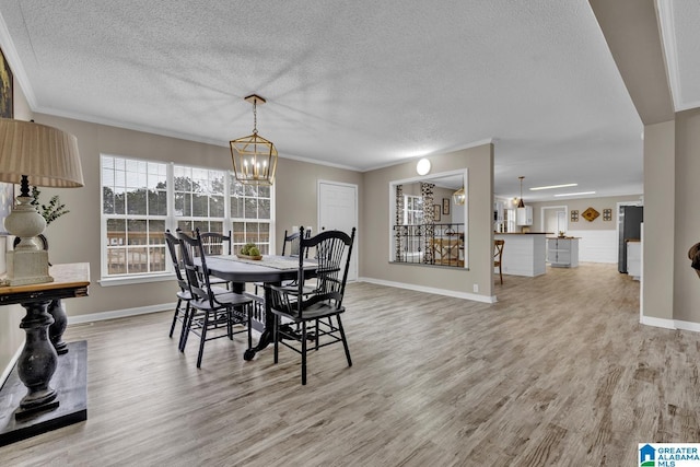 dining room featuring hardwood / wood-style floors, an inviting chandelier, a textured ceiling, and ornamental molding