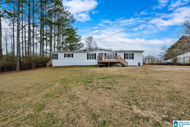 back of property with a lawn, an outbuilding, and a wooden deck