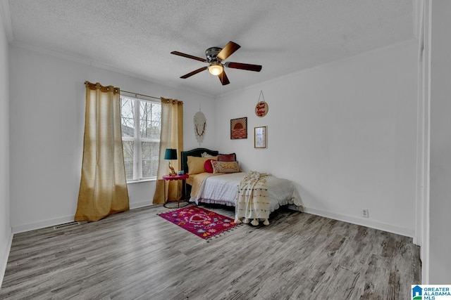 bedroom featuring ceiling fan, light hardwood / wood-style floors, a textured ceiling, and crown molding