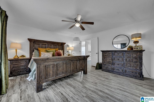 bedroom with ceiling fan, multiple windows, light hardwood / wood-style flooring, and a textured ceiling