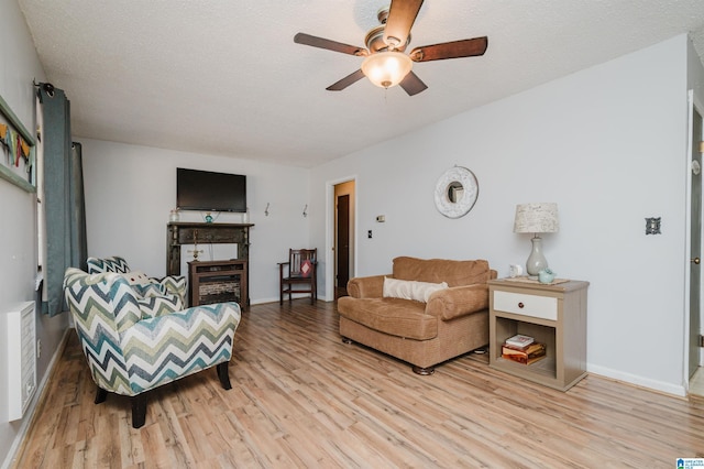 living room featuring ceiling fan, hardwood / wood-style flooring, and a textured ceiling