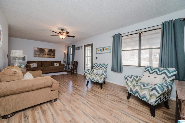 living room with ceiling fan, light hardwood / wood-style flooring, and a textured ceiling