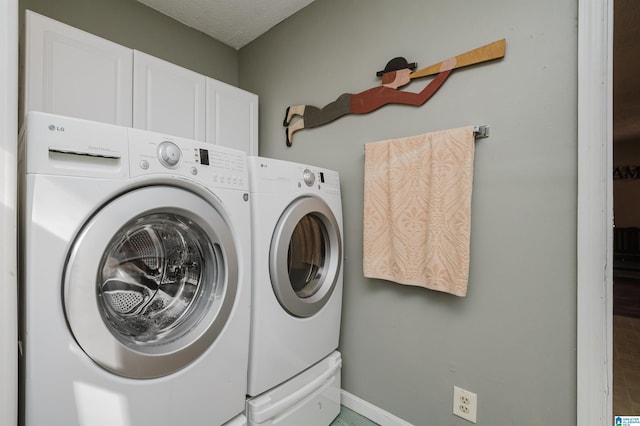 clothes washing area with cabinets and washer and dryer