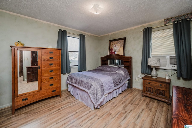 bedroom with cooling unit, a textured ceiling, and light wood-type flooring