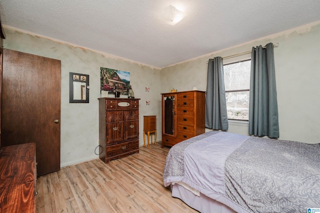 bedroom with a textured ceiling and light hardwood / wood-style flooring