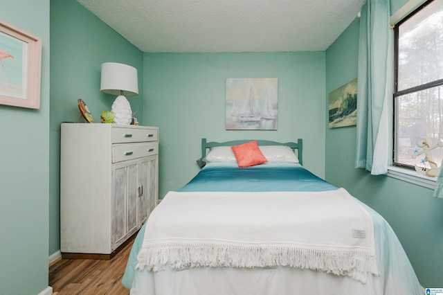 bedroom featuring multiple windows, a textured ceiling, and light hardwood / wood-style flooring