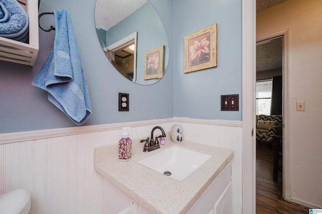 bathroom with vanity, hardwood / wood-style floors, a textured ceiling, and wood walls