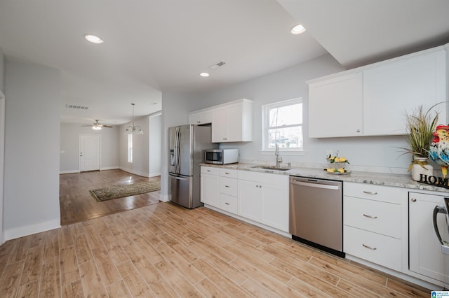 kitchen with white cabinets, appliances with stainless steel finishes, sink, and light wood-type flooring