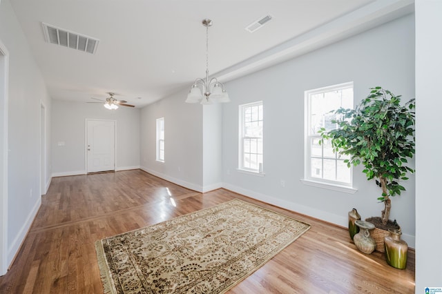 interior space with ceiling fan with notable chandelier and hardwood / wood-style floors