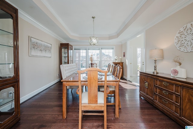 dining room with an inviting chandelier, crown molding, dark wood-type flooring, and a raised ceiling