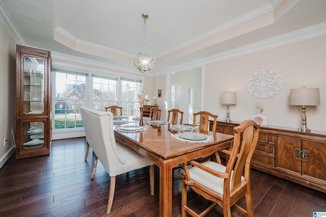 dining area with crown molding, dark wood-type flooring, a notable chandelier, and a tray ceiling