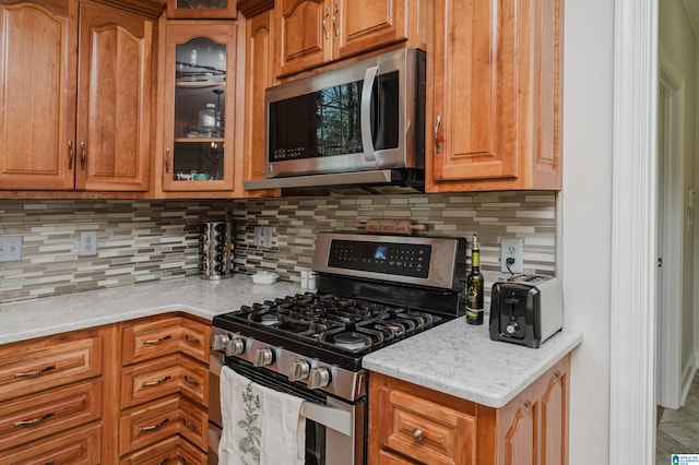 kitchen with light stone counters, tasteful backsplash, and stainless steel appliances