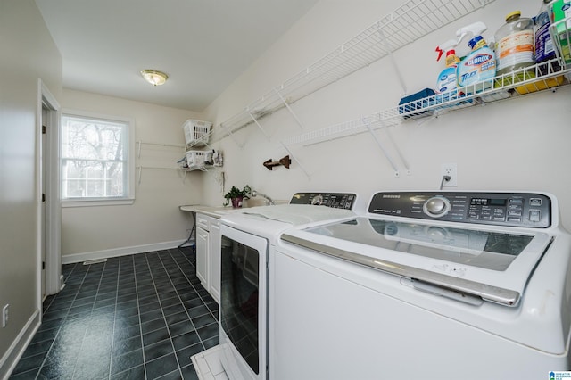 laundry room with washer and clothes dryer, cabinets, and dark tile patterned floors