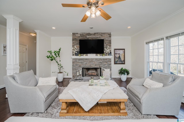 living room with ornate columns, crown molding, a stone fireplace, and hardwood / wood-style floors