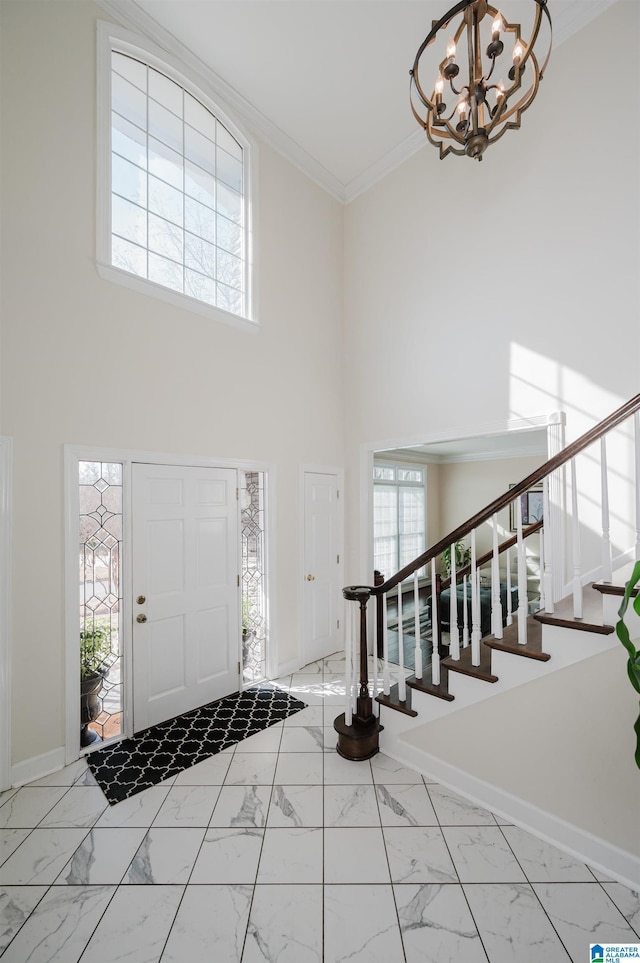 foyer featuring an inviting chandelier, ornamental molding, and a high ceiling