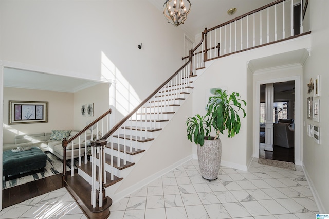 stairway with a high ceiling, crown molding, and a chandelier