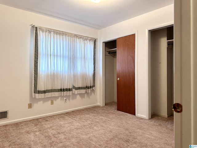 unfurnished bedroom featuring light colored carpet and a closet